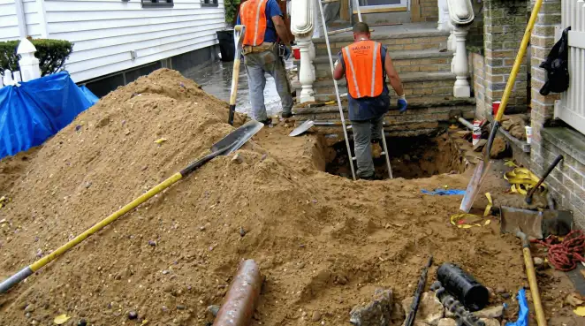 Contractors performing foundation protection and exterior drainage excavation near residential home steps in Manchester, NH